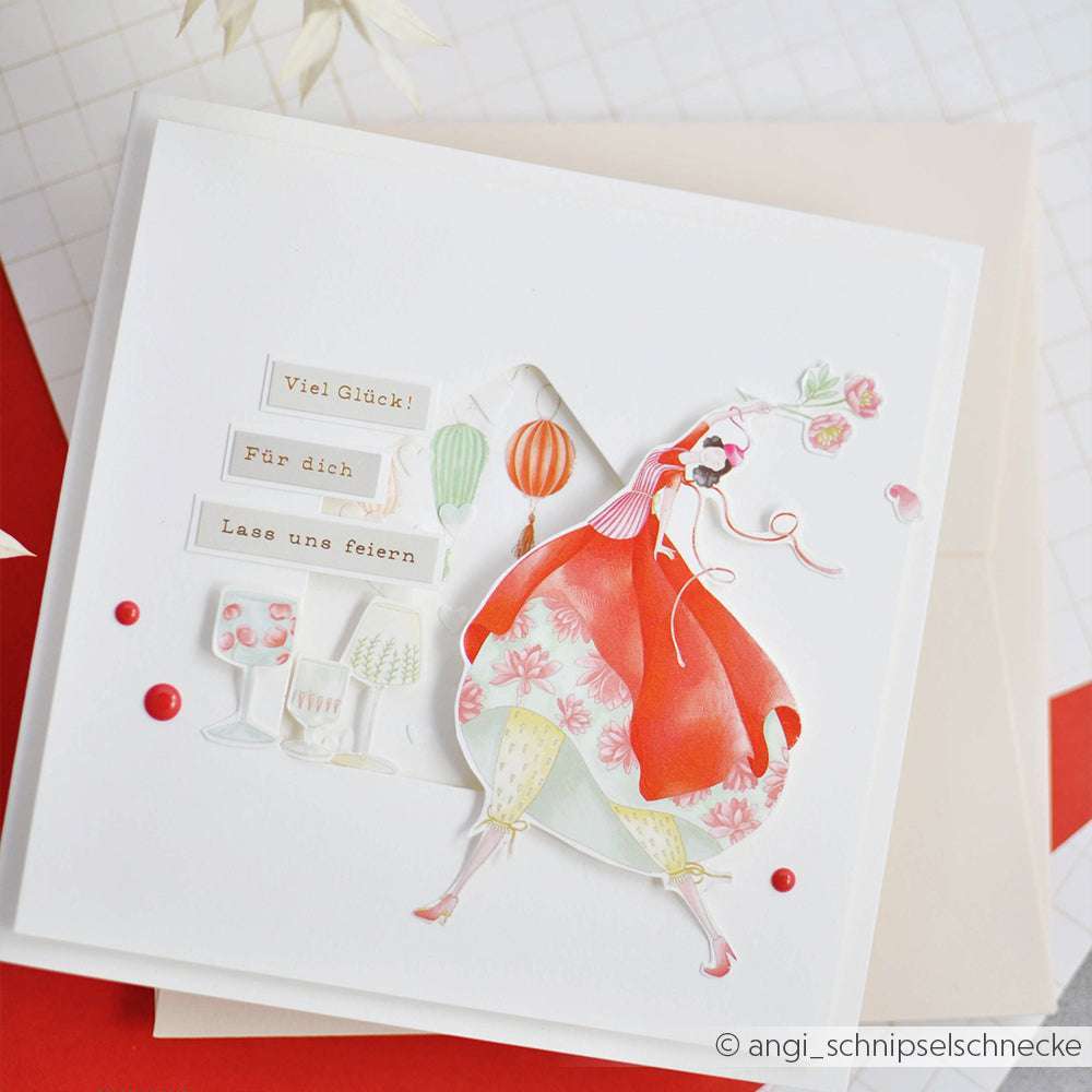 Handgemachte Grußkarte von Alexandra Renke mit einer tanzenden Frau in Rot, Getränken, Laternen und Glückwünschen - ideal für Bastelprojekte oder Ihre Figurenwelt Freizeit Kollektion mit Rub-On Transferfolien.