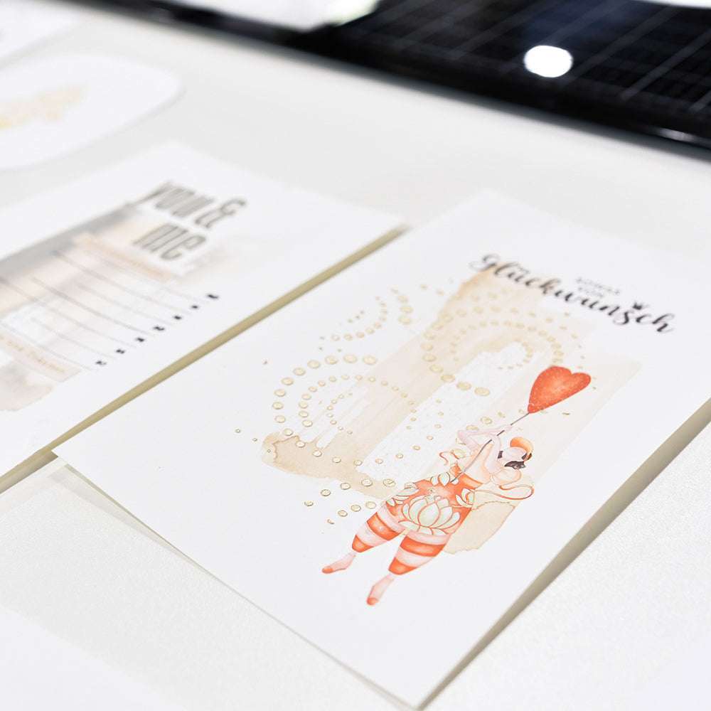 Eine Nahaufnahme von Alexandra Renke Dekokarten auf einem Tisch, darunter eine mit einer illustrierten Figur, die einen roten herzförmigen Luftballon hält - ideal für Rub-On Motiv oder Transferfolien Basteln.