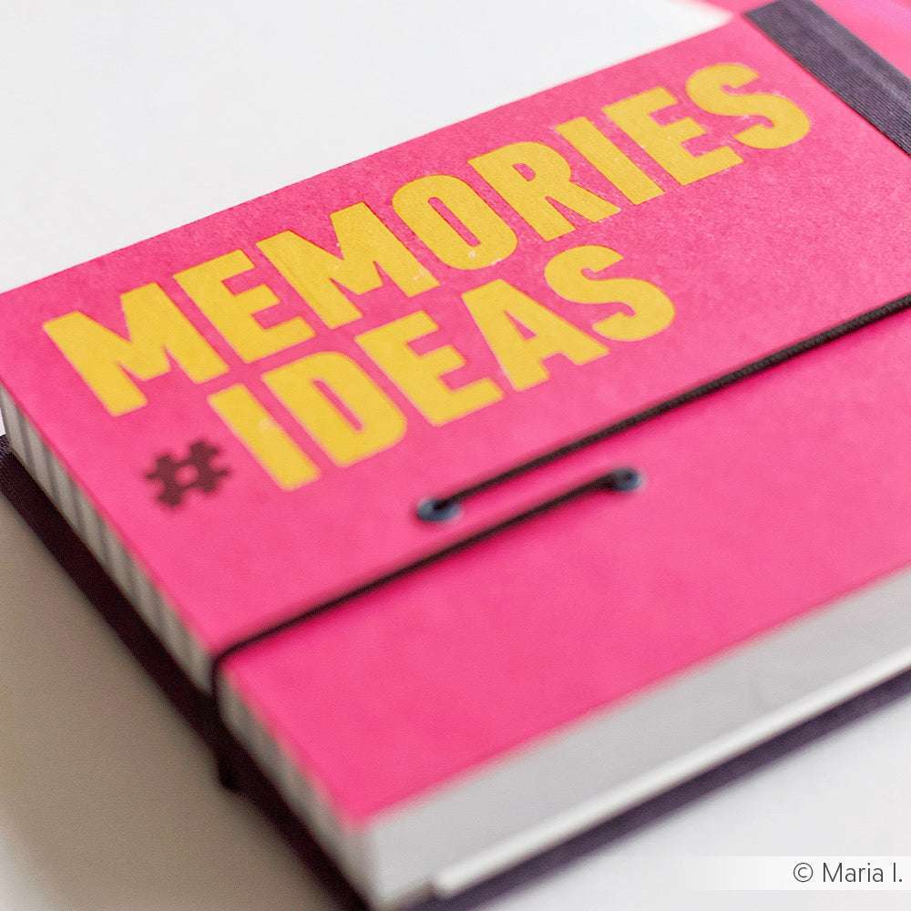 Ein rosafarbenes Notizbuch von Alexandra Renke mit MEMORIES #IDEAS in kräftigem Gelb - ideal, um Bastelprojekte-Motive zu notieren oder Rub-On Happy Words auszuprobieren, die Sie beim Basteln inspirieren.