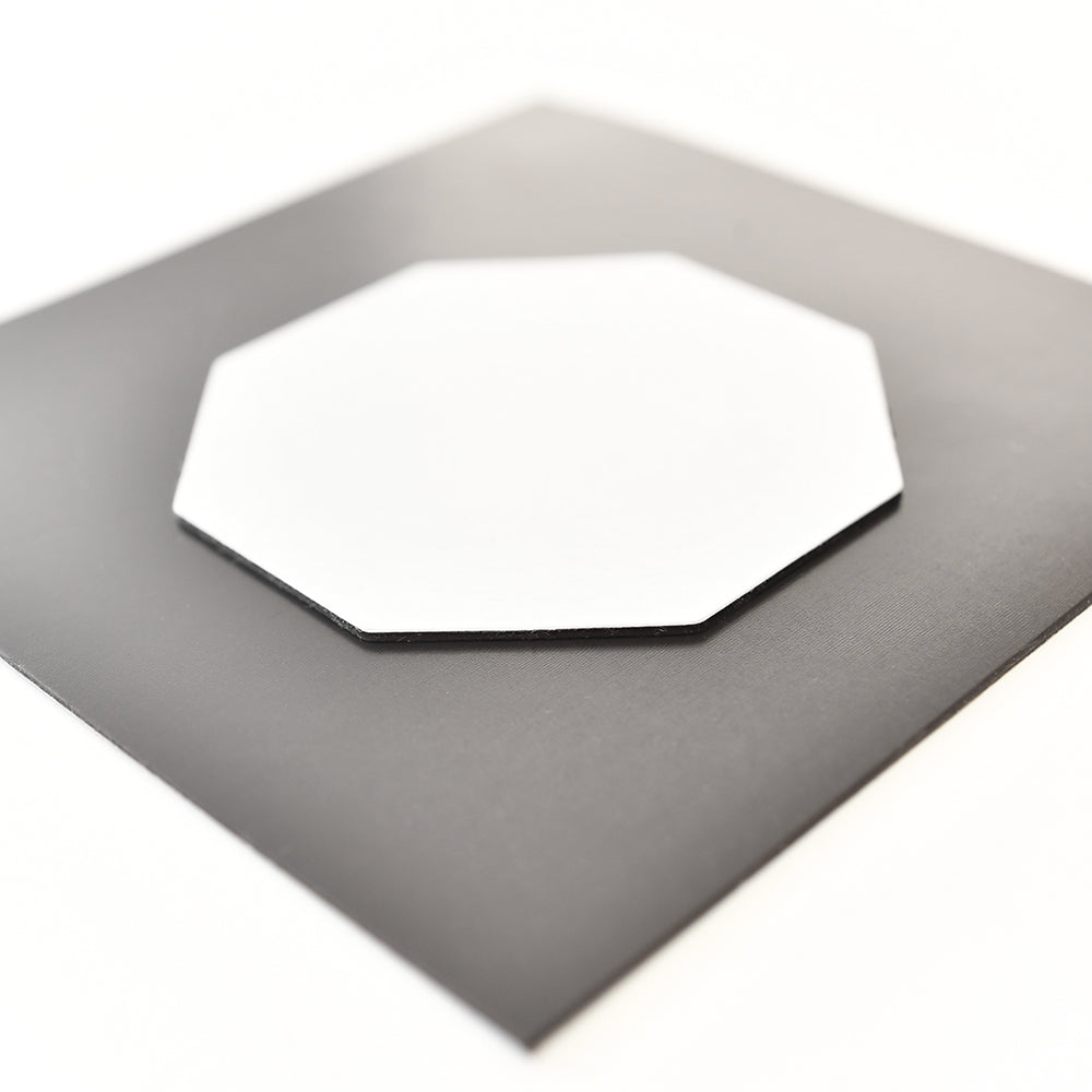 Ein weißes Achteck sitzt auf einem größeren schwarzen Quadrat, beide auf einer weißen Oberfläche - eine stilvolle Kühlschrankmagnete von ☆, die Ihre Kücheneinrichtung aufwertet.