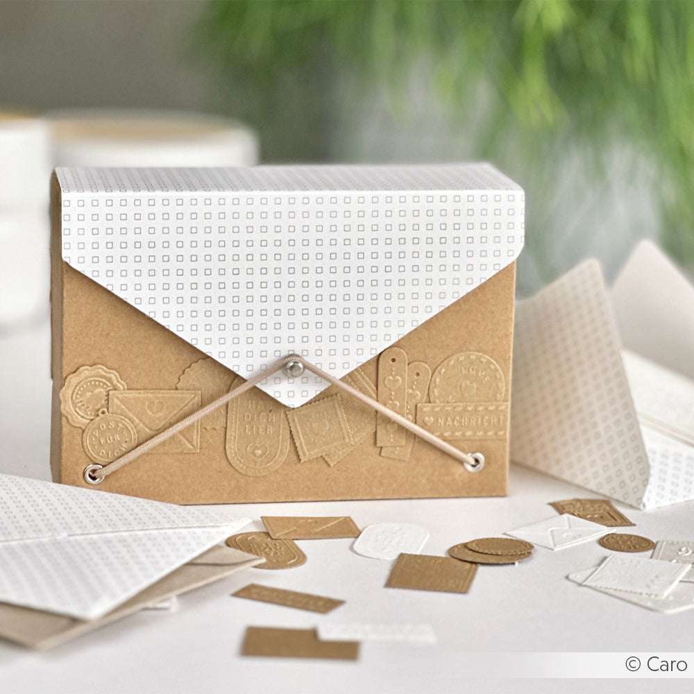 Eine dekorative braun-weiße Geschenkverpackung der Marke ☆ mit Schnurverschluss, umgeben von Papierformen auf einem Tisch.