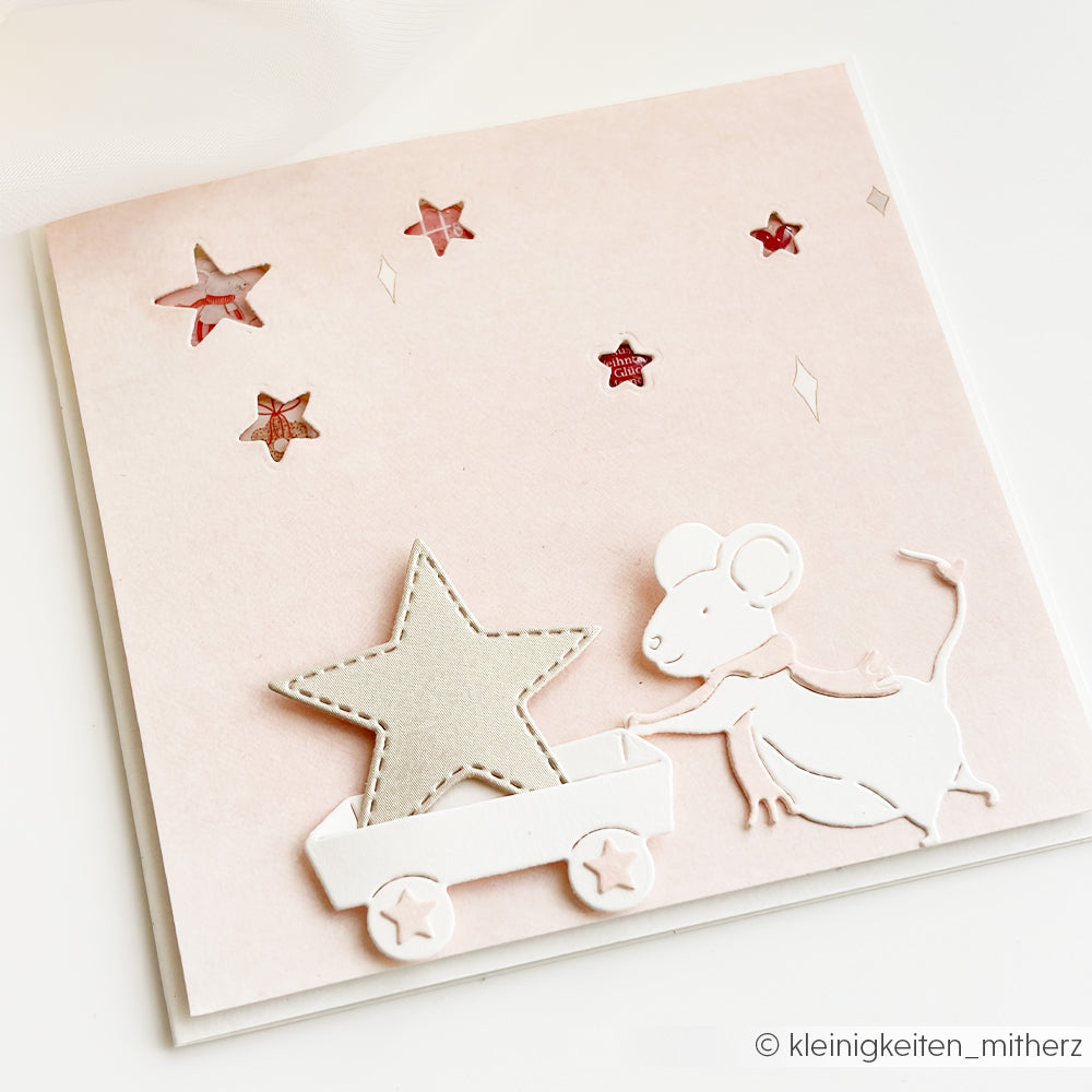 Eine Grußkarte mit einer Papiermaus, die einen Wagen und einen Stern zieht – perfekt für Weihnachtsmäuse-Motive.