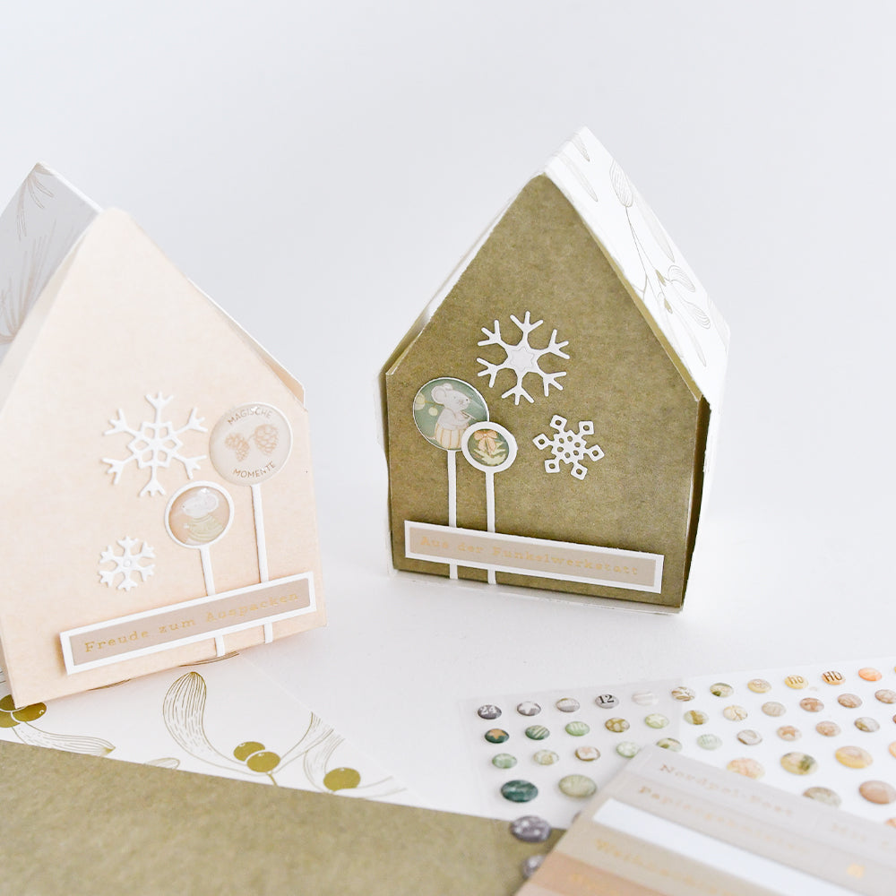 Zwei Geschenkboxen aus Büttenpapier mit Schneeflocken-Aufklebern für eine festliche Kartengestaltung.
