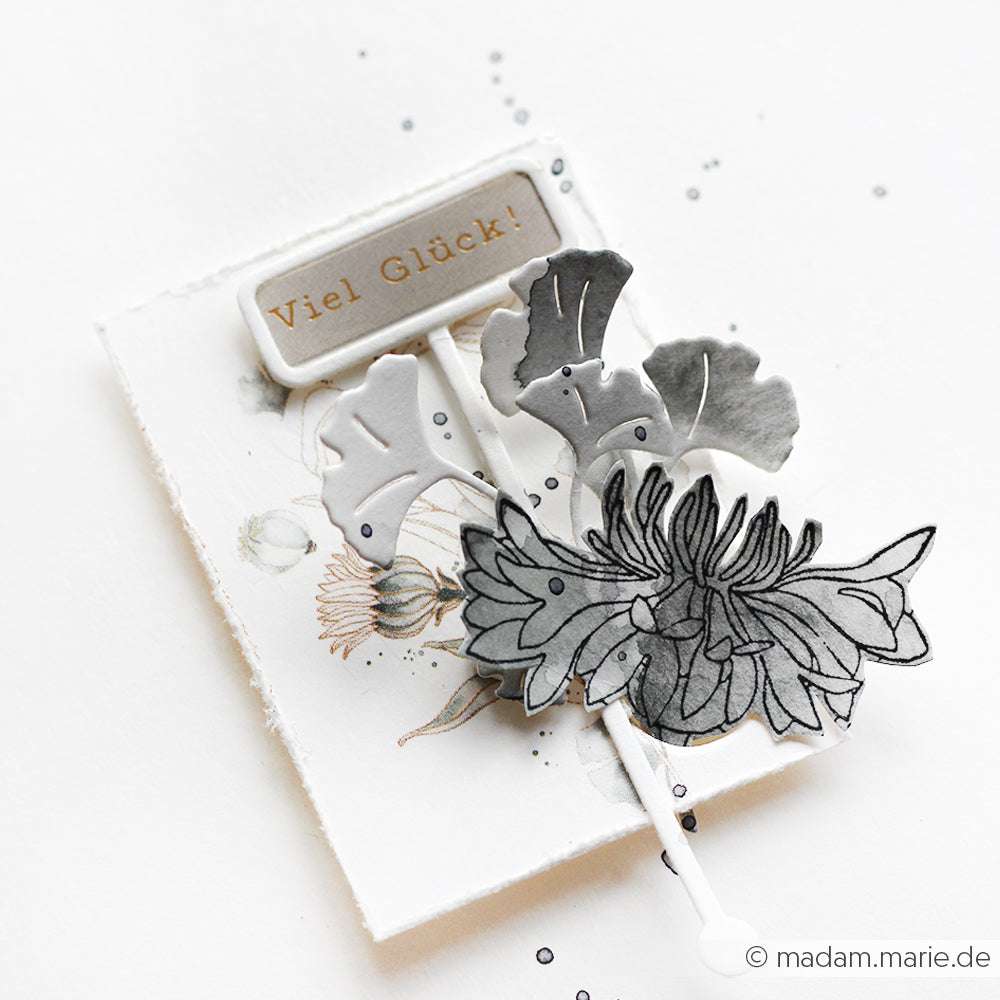Handgefertigte Karte von Alexandra Renke mit "Viel Glück!"-Schriftzug, grauen Blättern und schwarzem Blumenmuster auf weißem Grund - perfekt zum Basteln von Karten oder zum Verzieren mit Aufkleberstreifen.
