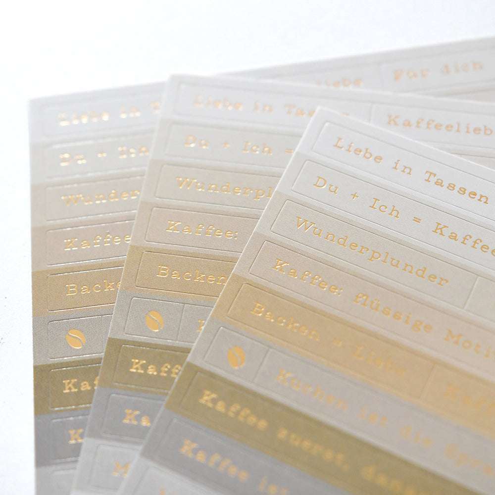 Überlappende Blätter mit goldgeprägten Sticker-Streifen von Alexandra Renke mit deutschen Sprüchen - ideal für die kreative Kartengestaltung.