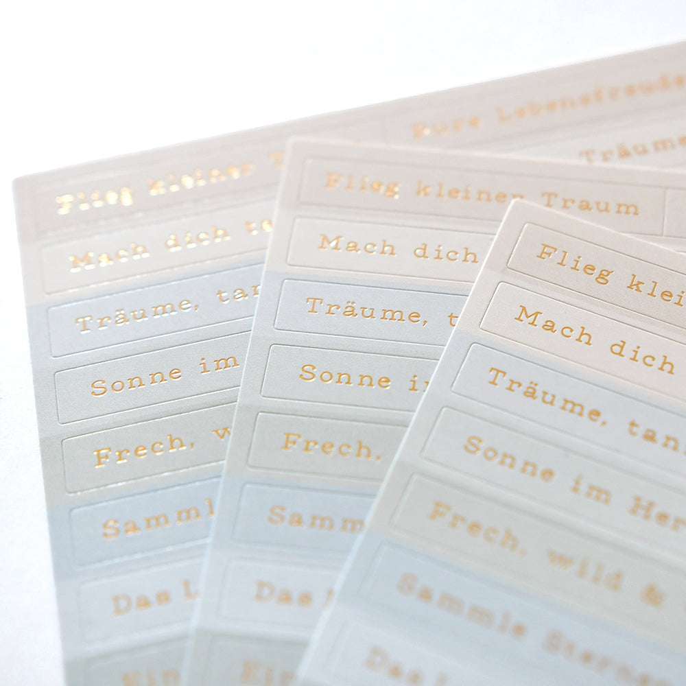 Bögen weißer Alexandra Renke Sticker-Streifen mit goldenem Text, ideal für die Kartengestaltung, übersichtlich angeordnet auf hellem Hintergrund.