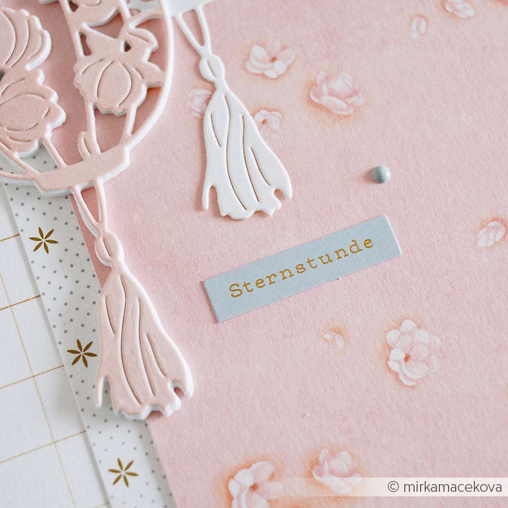 Nahaufnahme einer rosa geblümten Alexandra Renke Karte mit weißen Quastenausschnitten, Sticker-Streifen und einem "Sternstunde"-Etikett - ideal für kreative Kartengestaltung oder zum Verzieren Ihrer besonderen Momente.