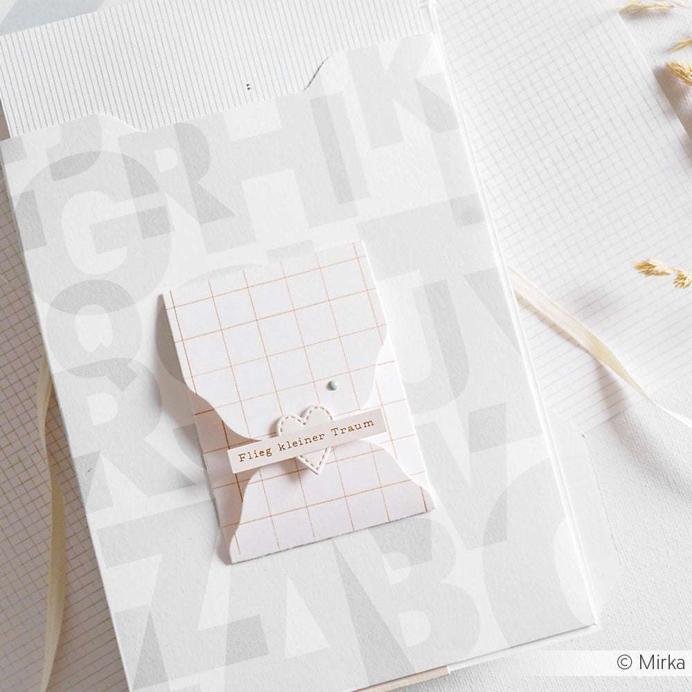 Eine kleine Karte von Alexandra Renke mit einem Gittermuster und einem Herz mit der Aufschrift "Flieg kleiner Traum", ideal für die Kartengestaltung oder zum Verzieren von Geschenken, abgebildet auf einem weißen strukturierten Hintergrund.