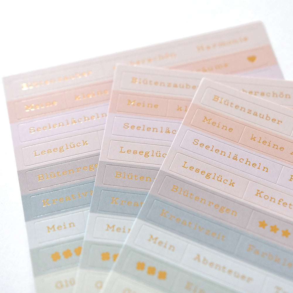 Drei Bögen Alexandra Renke Pastellsticker mit deutschen Wörtern und goldenen Symbolen - ideal für die Kartengestaltung oder um einen Hauch von Blütenzauber in Ihre Projekte zu bringen.