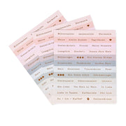 Drei pastellfarbene Stickerbögen von Alexandra Renke mit deutschen Wörtern und kleinen Symbolen in ordentlichen Reihen - perfekt für die Kartengestaltung oder um Ihren Projekten einen Hauch von Blumenzauber zu verleihen.