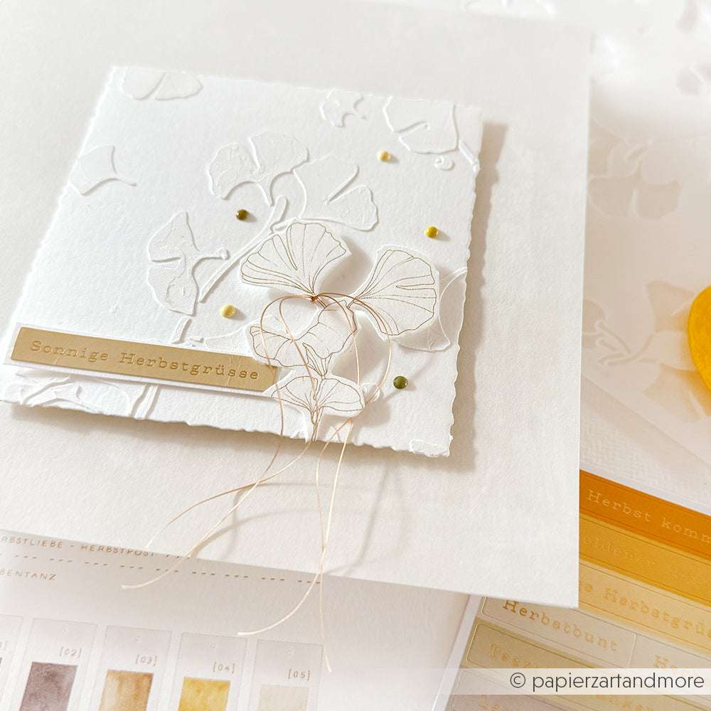 Weiße Prägekarte mit zartem Blattmotiv, Goldfaden und dem Label "Sonnige Herbstgrüße" von Alexandra Renke - eine wunderschöne Kartenkreation für den Goldenen Herbstzauber.