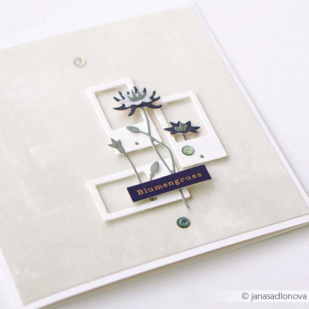 Handgefertigte Karte von Alexandra Renke mit geschichteten weißen Rahmen, blauen Blumen und einem "Blumengrüße"-Schriftzug auf hellem Hintergrund, akzentuiert mit zarten Sticker-Streifen für eine elegante Note.