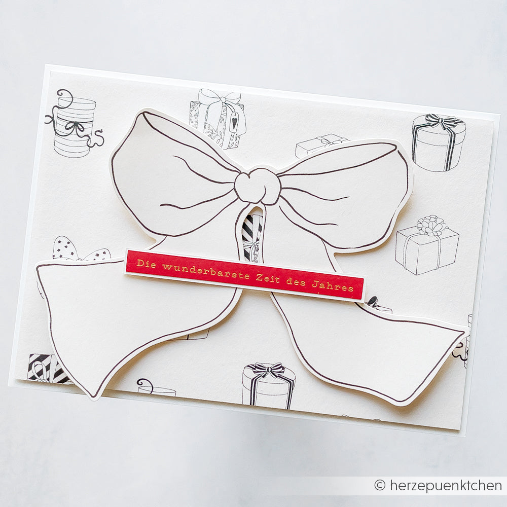 Eine Karte von Alexandra Renke mit einer großen konturierten Schleife, Geschenken und dem deutschen Text "Die wunderbarste Zeit des Jahres". Perfekt, um kreative Weihnachtskarten zu basteln und den Zauber der Feiertage einzufangen.
