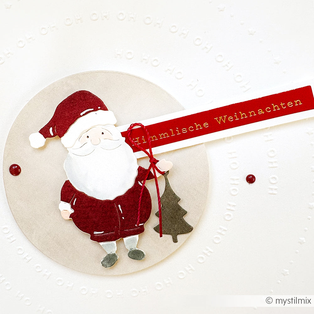 Weihnachtsmann aus Papier, der einen Baum mit "Himmlische Weihnachten" auf einem roten Banner hält, von Alexandra Renke - ideal für festliche Kartengestaltung und um Ihren kreativen Projekten Weihnachtszauber zu verleihen.