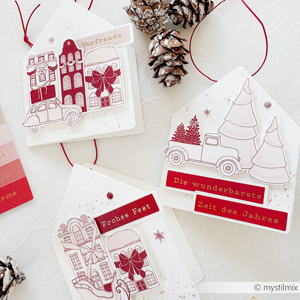 Drei festliche Geschenkanhänger von Alexandra Renke mit roten Weihnachtsmotiven, deutschen Grüßen und Tannenzapfen auf weißem Grund - ideal für die Kartengestaltung oder zum Hinzufügen von Zauber der Weihnacht zu Ihren Geschenken.