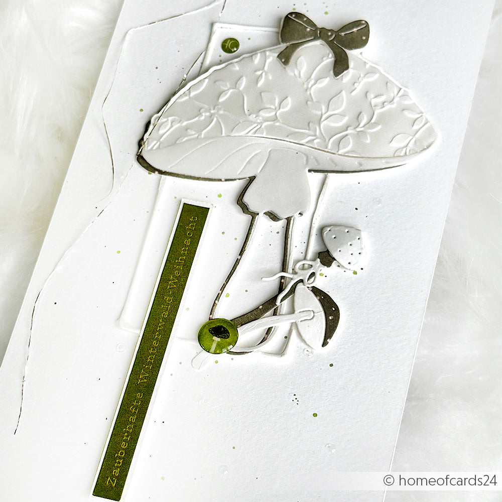 Handgefertigte Karte von Alexandra Renke mit einem geprägten weißen Pilz, grünen Akzenten und deutschem Text auf weißem Hintergrund - ideal für kreative Kartengestaltung im Stil des Winterwaldzaubers.