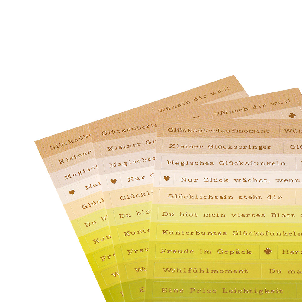 Vier Bögen mit „Glücksmomente“-Stickern von Alexandra Renke in Farbverläufen von Braun bis Gelb, fächerförmig angeordnet – ideal für die Kartengestaltung oder als kreative Akzente auf Stickerstreifen.