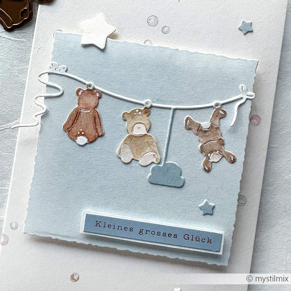 Eine Karte von Alexandra Renke mit Teddybären und einer Wolke auf einer Wäscheleine, mit dem deutschen Text "Kleines grosses Glück". Perfekt für die Begrüßung eines neuen Babys - "Willkommen im Leben!" Ideal für Grußkarten zur Geburt.