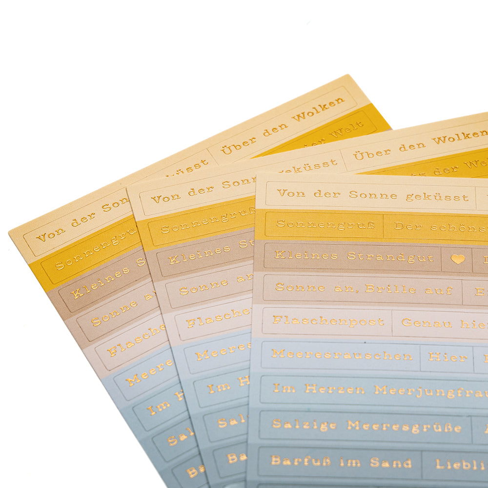Vier Bögen Alexandra Renke pastellfarbener Sticker-Streifen mit deutschen Sprüchen in Gold, aufgefächert - ideal für die Gestaltung von Karten oder um Ihren Bastelarbeiten einen Meeresbrise-Touch zu verleihen.
