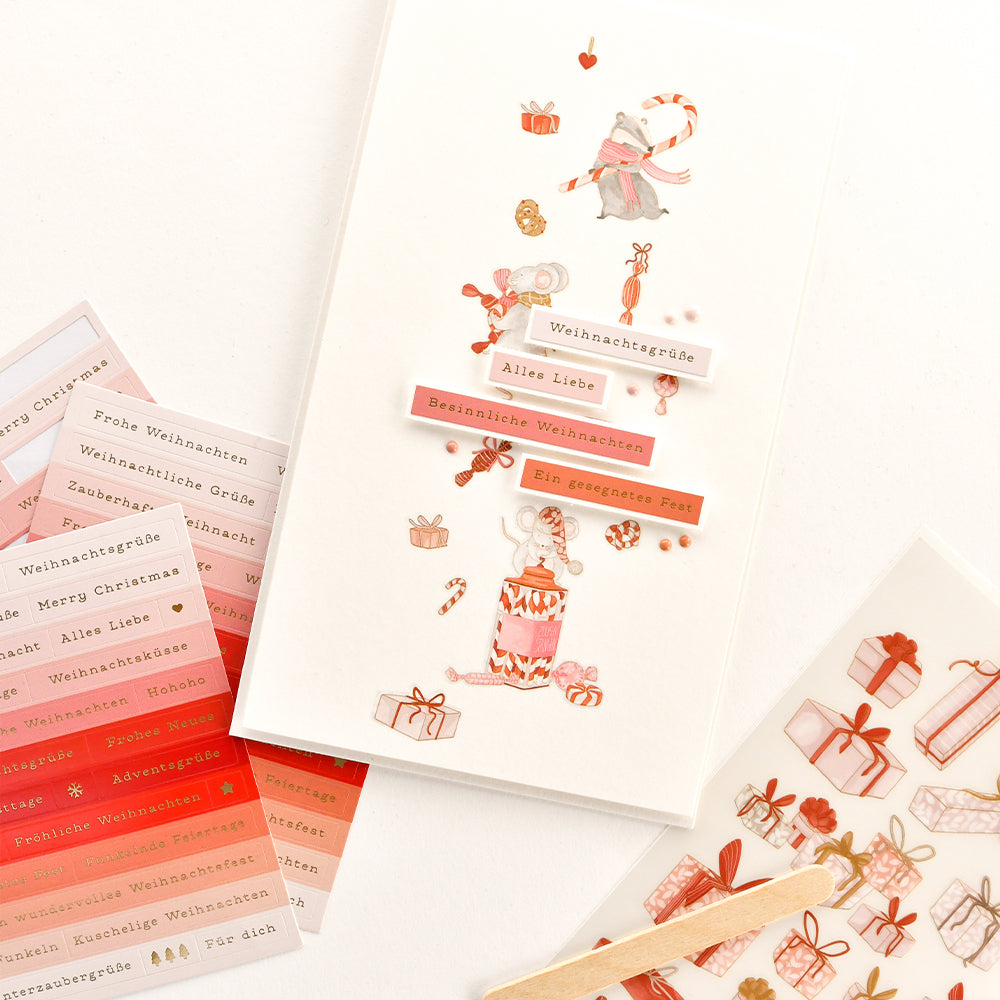 Weihnachtskarten-Aufkleber und ein Blatt Papier mit festlichen Aquarellillustrationen.