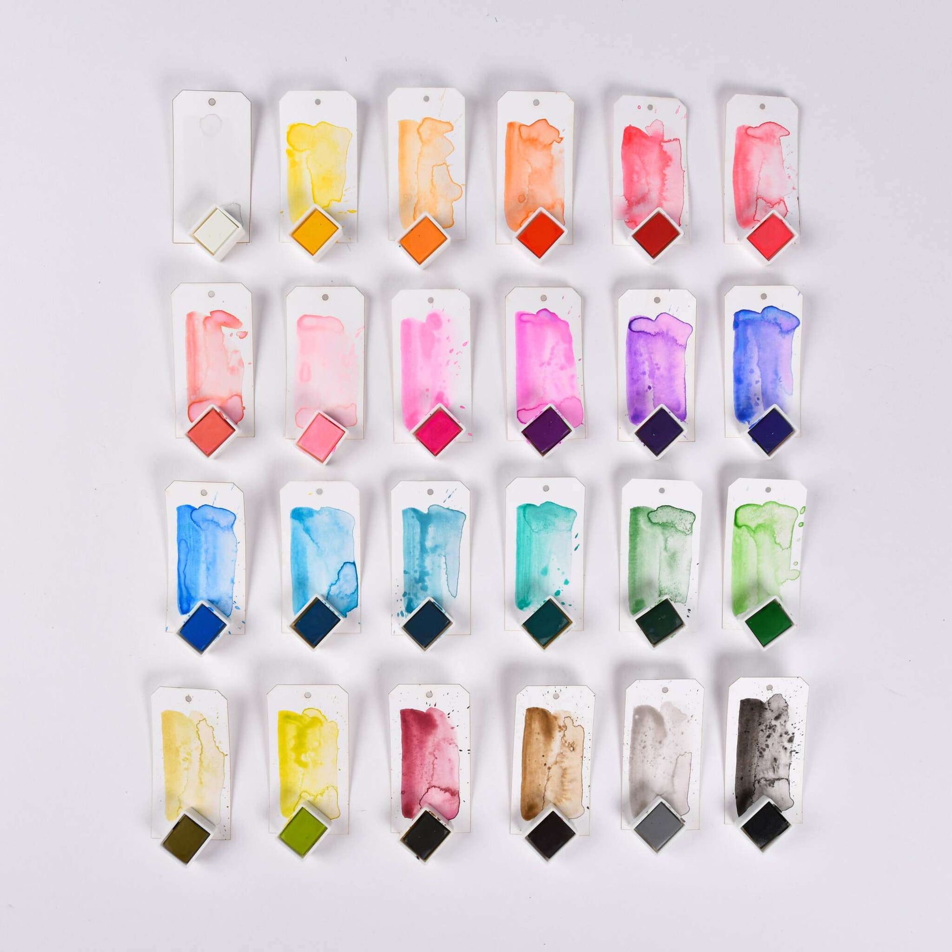 Zwanzig Aquarellfarben auf Anhängern, jeweils mit einer farbigen Farbwanne aus dem Set Studio Light Aquarellfarben, angeordnet in fünf Reihen auf weißem Hintergrund.
