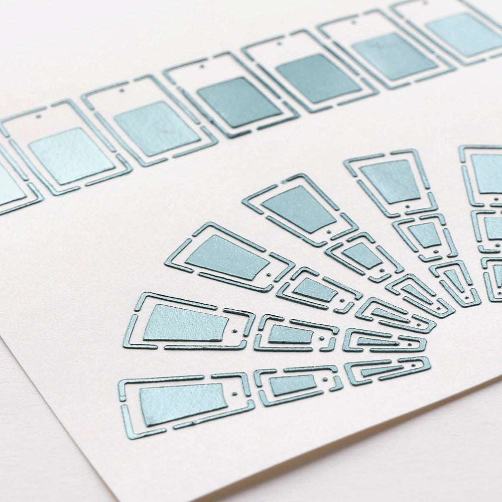 Metallisch blaue Smartphone-Symbole von Alexandra Renke, angeordnet in Linien und Fächerformen auf weißem Papier, erinnern an eine moderne Schablonenfarbkarte - ideal für kreative Projekte mit wiederverwendbaren Vorlagen.