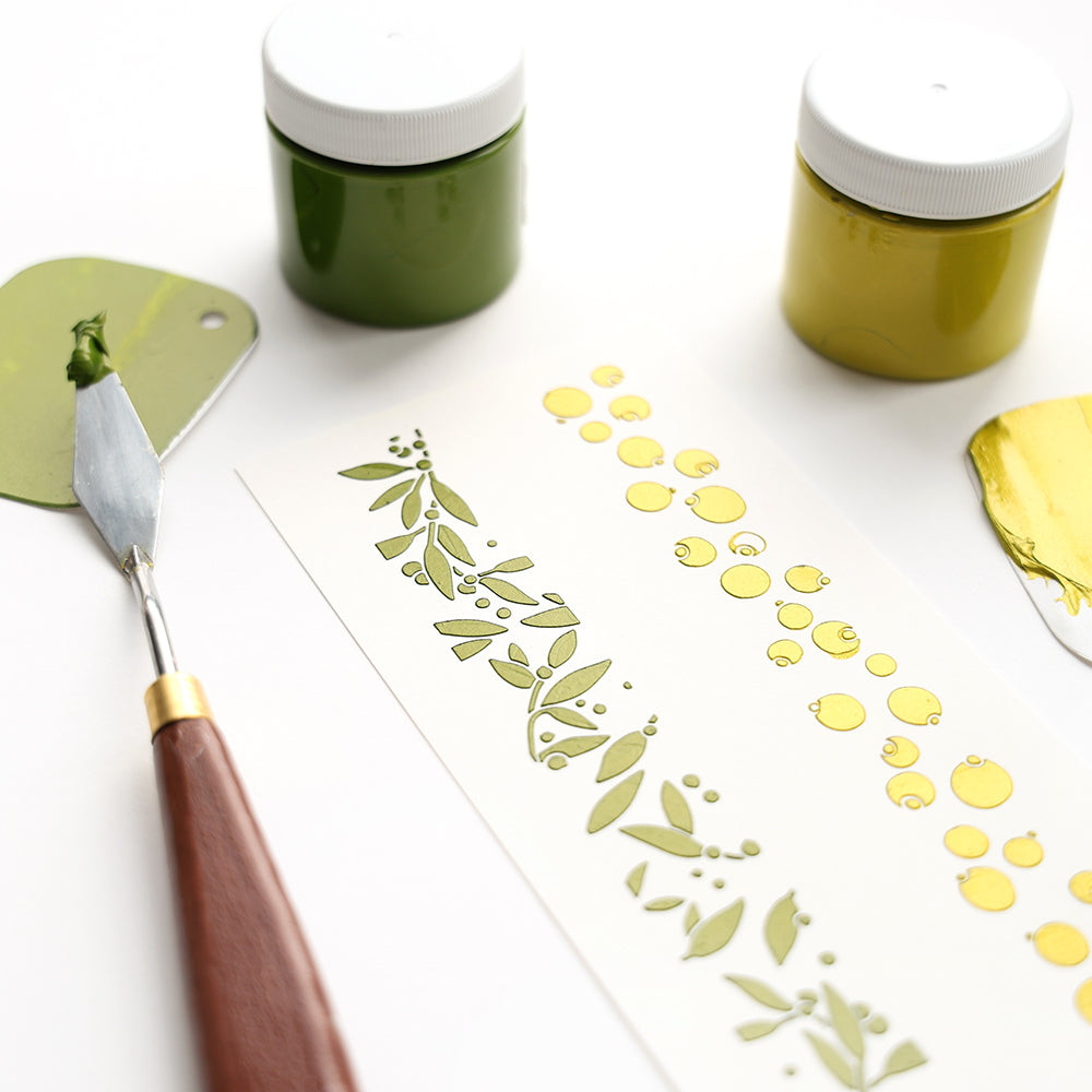 Mit einem Spachtel, zwei Gläsern grüner Farbe und Alexandra Renke wiederverwendbaren Schablonen wurde ein knackiges botanisches Stencil Musterstreifen Beeren-Design auf weißem Papier erstellt.