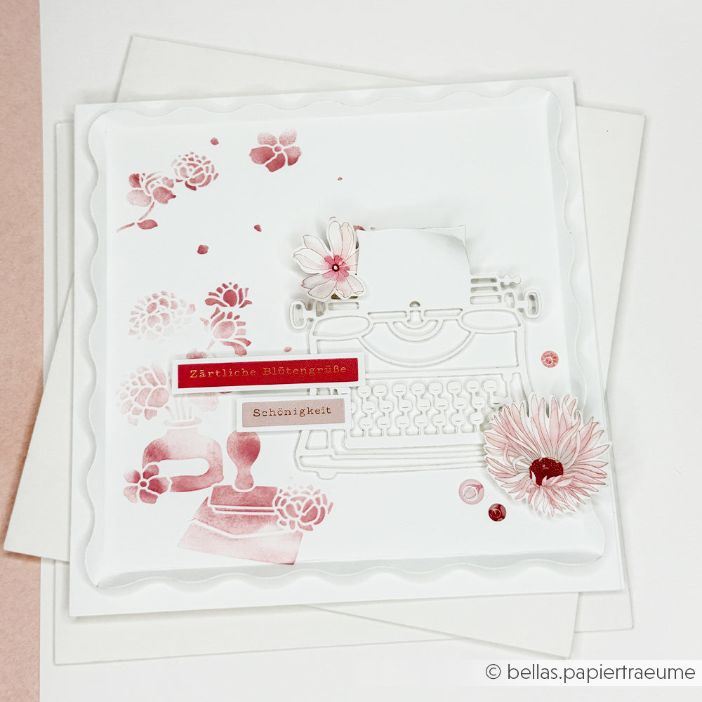 Weiße Karte mit rosa Blumenakzenten, einem Schreibmaschinen-Ausschnitt und deutschem Text auf einem mehrschichtigen Hintergrund, verziert mit der Schablone „Schreibliebe Wirbel“ aus der „wiederverwendbar“-Reihe von Alexandra Renke für eine künstlerische Note.