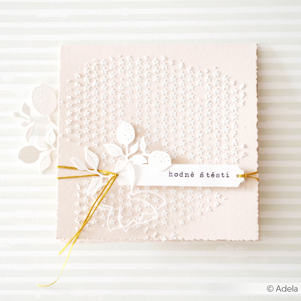 Beigefarbene, quadratische Karte mit weißen, geprägten Blumen, goldener Kordel und einem Anhänger mit der Aufschrift „hodně štěstí“. Das Design eignet sich perfekt für Schablonen-Papierprojekte und verfügt über ein zartes Schablonenraster, das für Ihre kreativen Projekte wiederverwendbar ist.