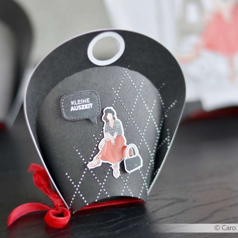 Elegante schwarze Geschenkbox mit roter Schleife von Alexandra Renke, mit einer Frauenillustration und dem Text "KLEINE AUSZEIT" - ideal für Schablonen Papierprojekte oder inspirierende wiederverwendbare Stencil Designs.