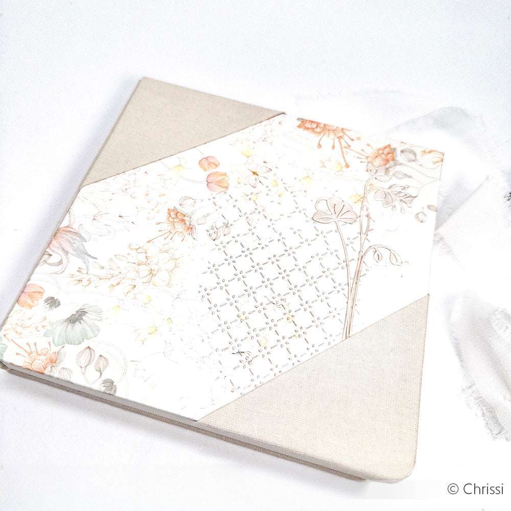 Ein floral gemustertes Alexandra-Renke-Notizbuch mit beigen Stoffecken, platziert auf einer weißen Oberfläche, beinhaltet wiederverwendbare Schablonen zum Erstellen eigener geometrischer Muster.