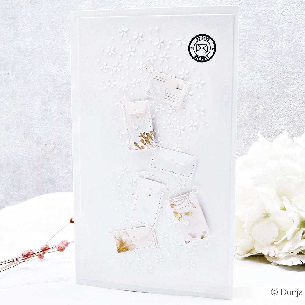 Handgemachte weiße Karte von Alexandra Renke mit kleinen Umschlägen, floraler Prägung, einem Poststempel und zarten Blumenschablonen - perfekt für kreative Schablonenpapierprojekte.