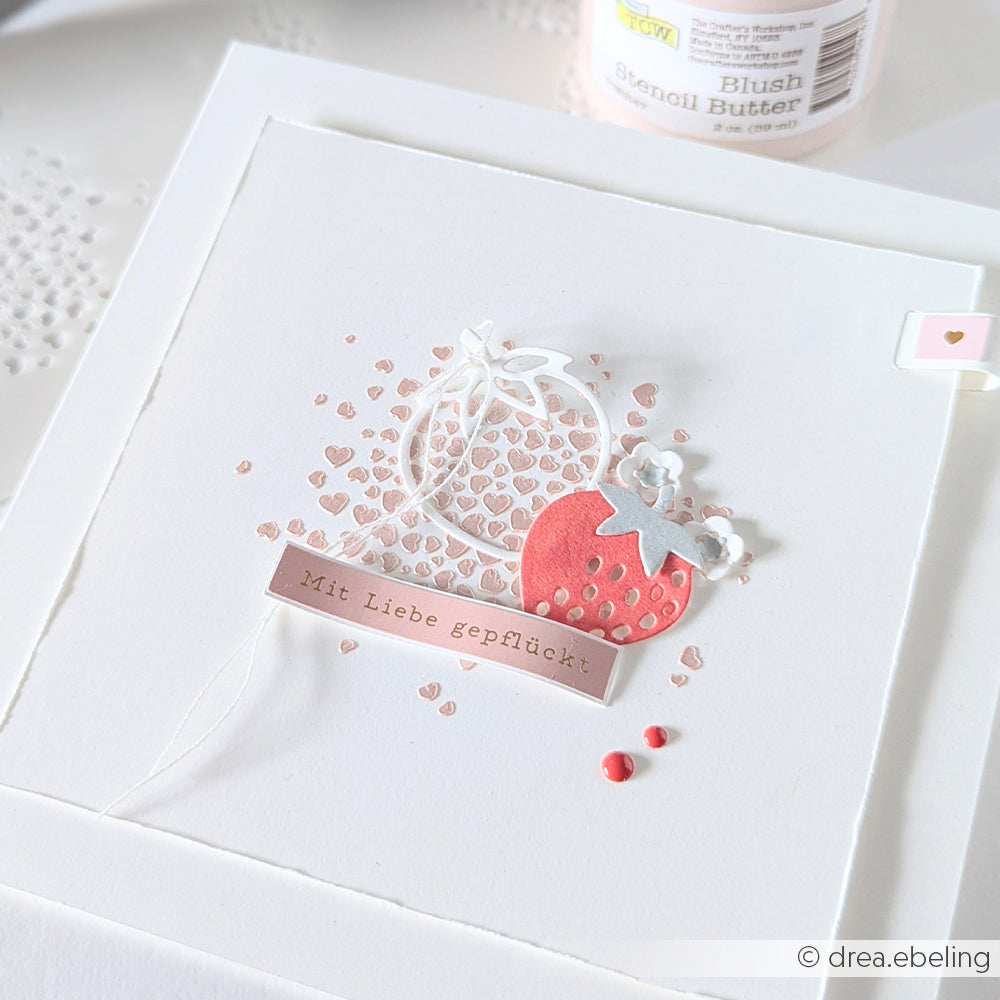 Handgefertigte Karte von Alexandra Renke mit einer roten Erdbeere, kleinen rosa Herzen und der deutschen Botschaft "Mit Liebe gepflückt", akzentuiert mit der Schablone Herz voller Herzen Schablone für zusätzlichen Charme.