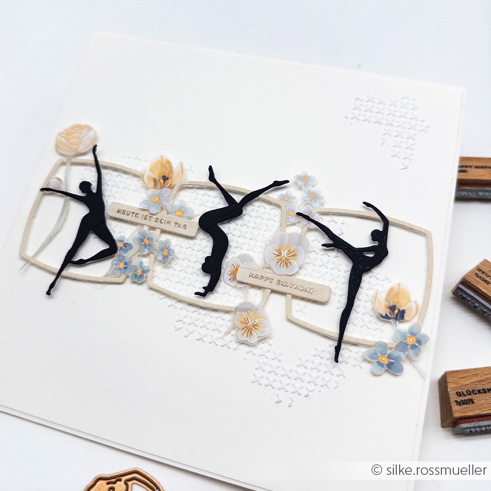 Eine handgefertigte Karte mit schwarzen Ballerina-Silhouetten, pastellfarbenen Blumen und einem strukturierten weißen Hintergrund, der mit einer wiederverwendbaren Schablone von Alexandra Renke gestaltet wurde und der Karte zusätzlichen Charme verleiht.