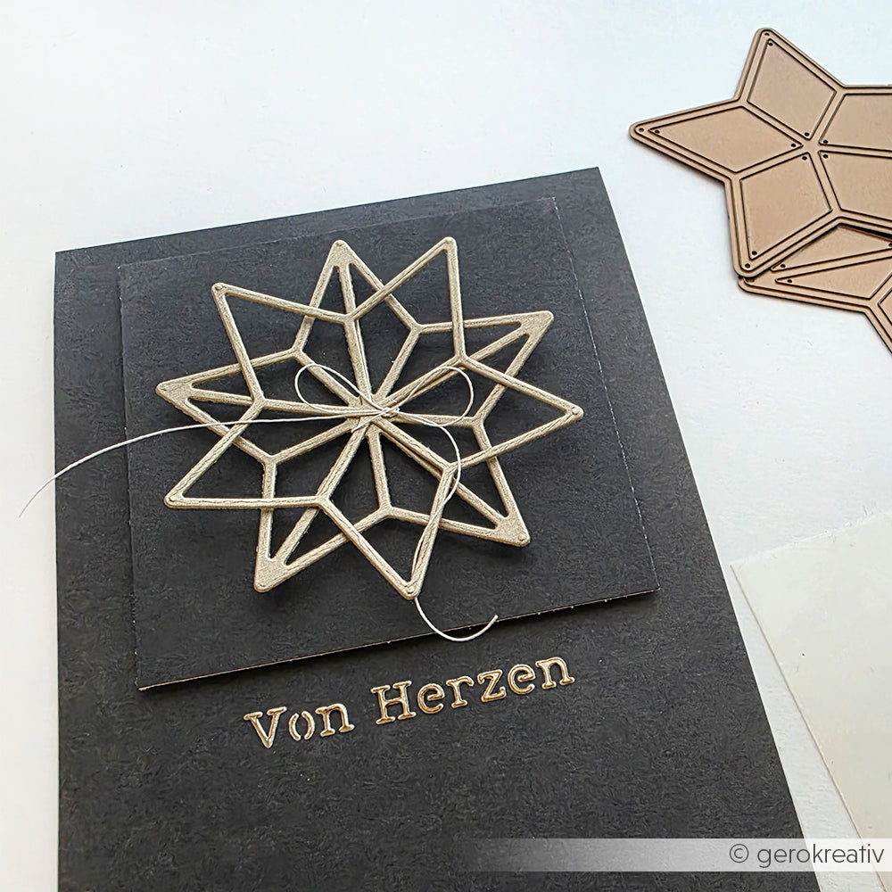 Eine schwarze Alexandra Renke Karte mit einem 3D-Stern und goldenem "Von Herzen"-Text neben einem gestanzten Metallstern - perfekt für Ihre Weihnachtsfest-Schablone oder Schablonen Papierprojekte.