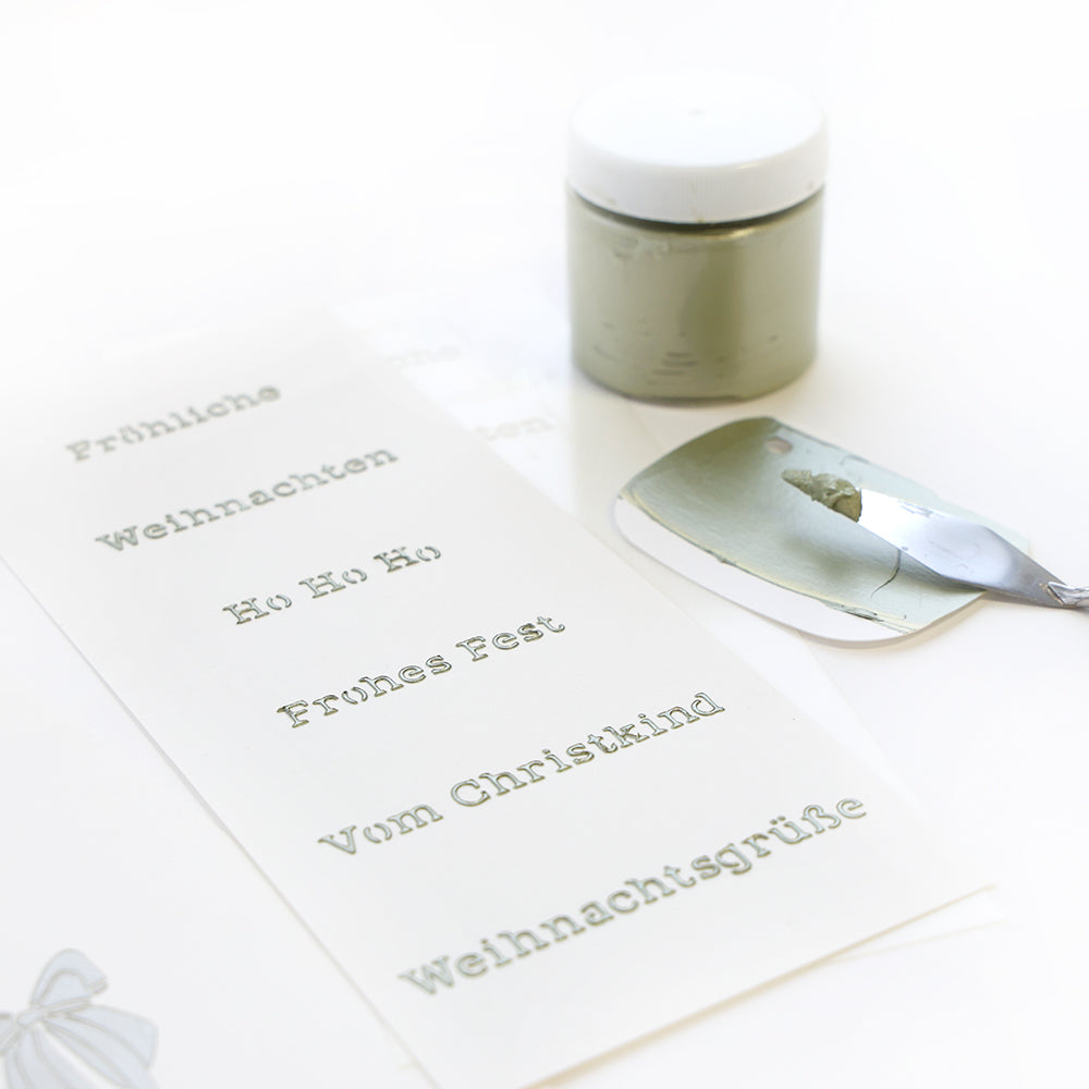 Ein Bogen mit deutschen Festtagssprüchen, Alexandra Renke Farbe und ein Spachtel - ideal für festliche Schablone Papierprojekte oder Ihr wiederverwendbares Stencil Frohes Fest Design.