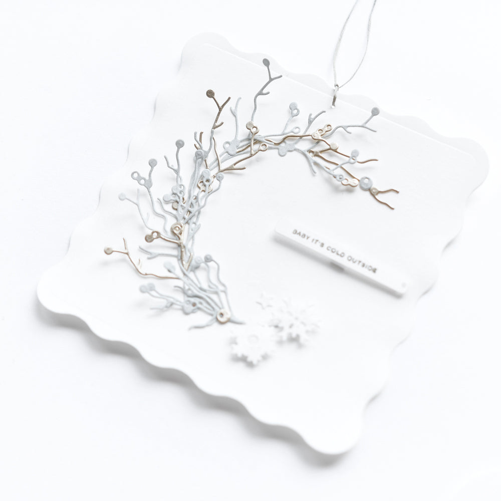 Weißes Ornament mit zarten Zweigen, hergestellt mit dem Alexandra Renke Beeren Zweige Trio, zeigt "Baby it's cold outside" auf einem gezackten Quadrat - ideal für Designpapiere oder in Kombination mit Ihren Lieblings-Stanzsystemen.