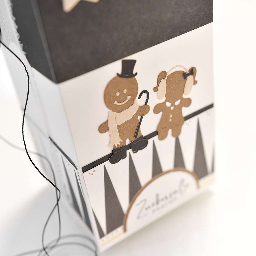 Lebkuchenfiguren aus Alexandra Renke Designpapieren und Die Motivstanze Lebkuchen Vater und Tochter - eine davon mit Zylinder und Stock - werden in einer schwarz-weiß gemusterten Geschenkbox präsentiert.