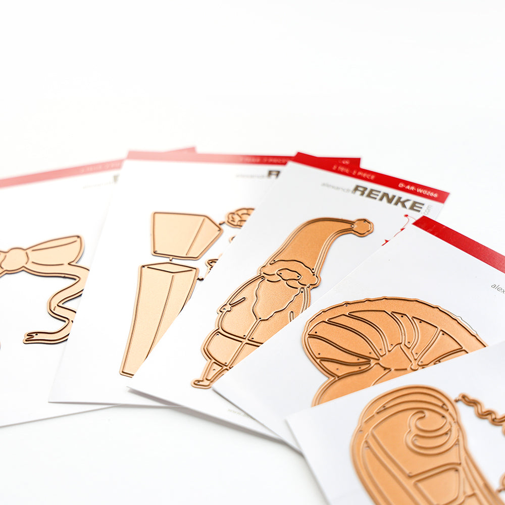 Vier gestanzte Metallschablonen auf weißen Karten mit weihnachtlichen und festlichen Motiven, die fächerförmig angeordnet sind.