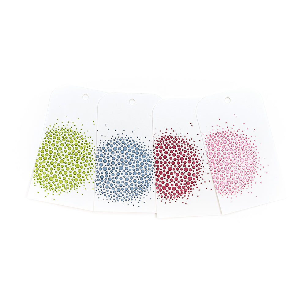 Vier weiße Karten mit kreisförmigen Punktmustern in Grün, Blau, Rot und Rosa – jede davon mit „Stencil Butter“ von The Crafter’s Workshop, Inc. gestaltet, um ein sattes, strukturiertes Finish zu erzielen – weisen oben ein Loch auf. Perfekt für Mixed-Media-Projekte oder zum Experimentieren mit Modellierpaste-Techniken.