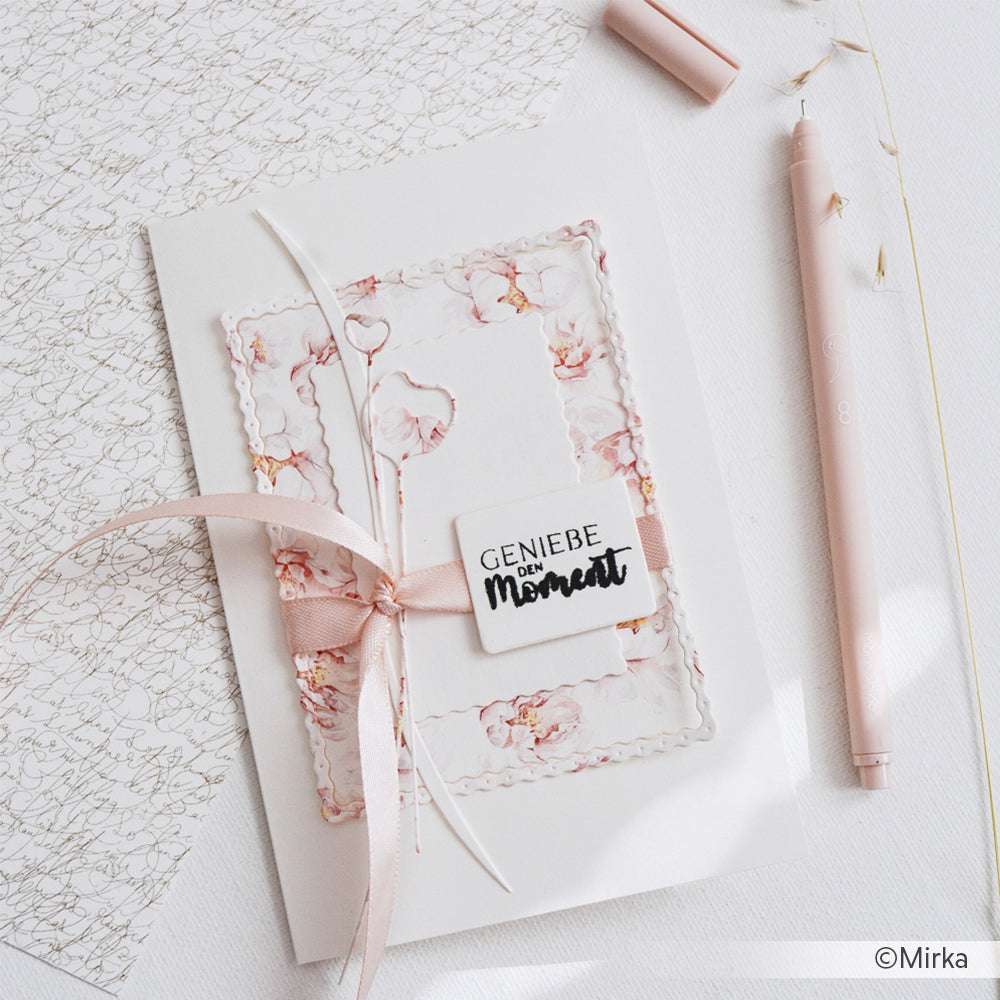 Elegante florale Grußkarte mit rosa Schleife, hergestellt mit den Motivstanze Dies von Alexandra Renke aus dem Set Artistblumen, neben einem rosa Stift und handgeschriebenem Schreibpapier.