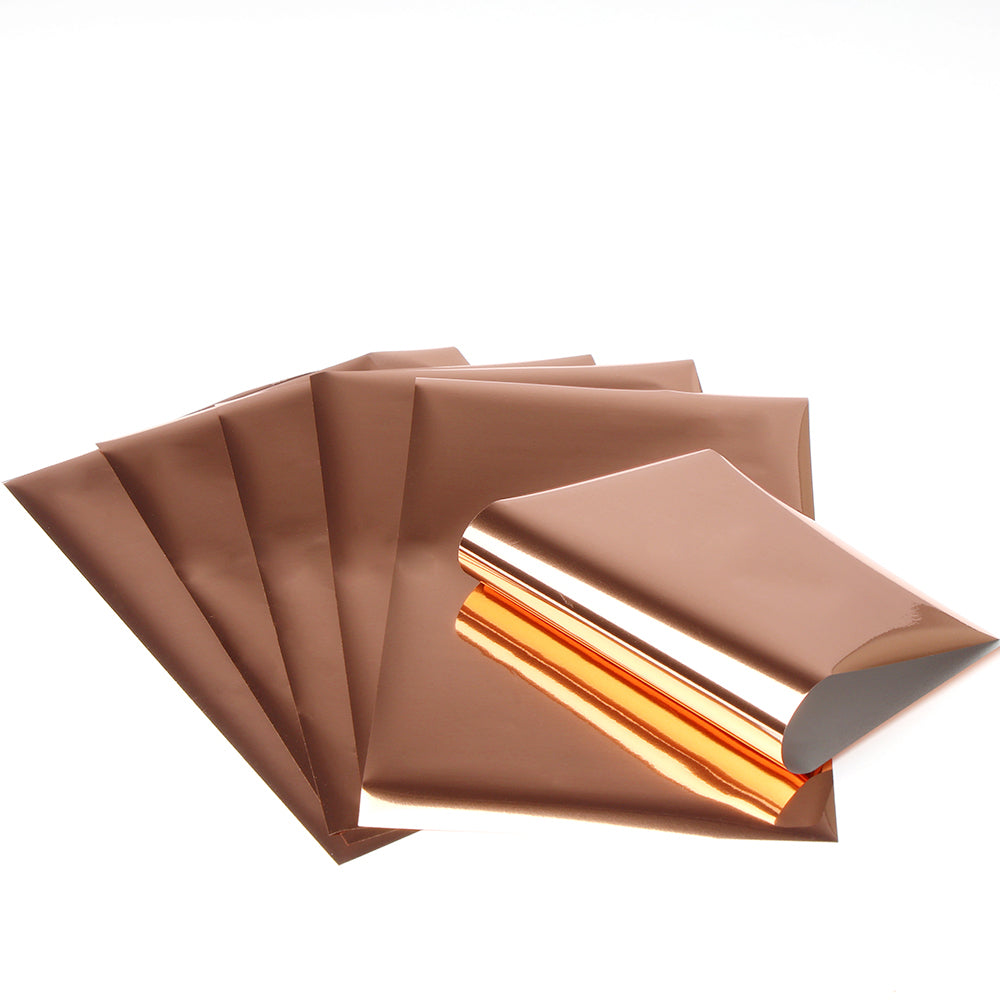 Fünf Bögen kupferfarben glänzender Rico Design Transferfolie, gestapelt und aufgefächert auf weißem Hintergrund - ideal für Paper Poetry Projekte und metallische Verzierungen.