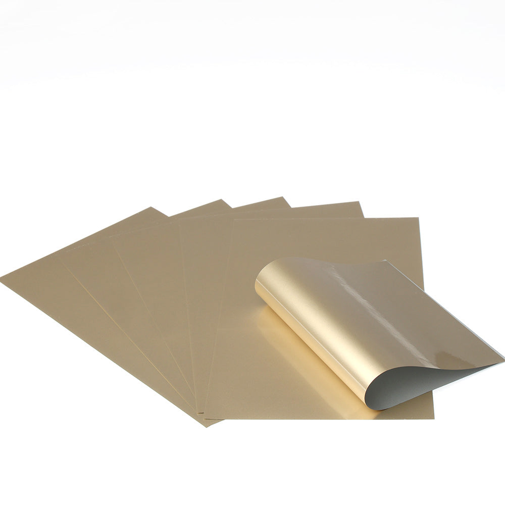 Fünf Bögen goldglänzendes Metallic-Papier von Rico Design, ideal für Metallic-Dekorationen oder zur Verwendung mit Transferfolie; ein Bogen ist an der Ecke teilweise gewellt und steht auf weißem Hintergrund.
