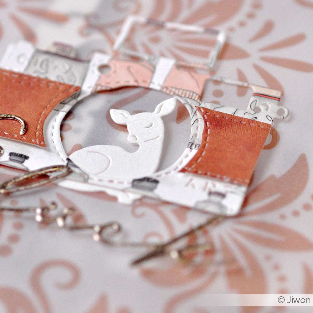 Ein Papierausschnitt einer Kamera mit einem Reh in der Mitte, hergestellt mit Alexandra Renke Stanzsysteme, ruht auf einem floral gemusterten Hintergrund - ideal für Ihr nächstes Dies für Basteln-Projekt.