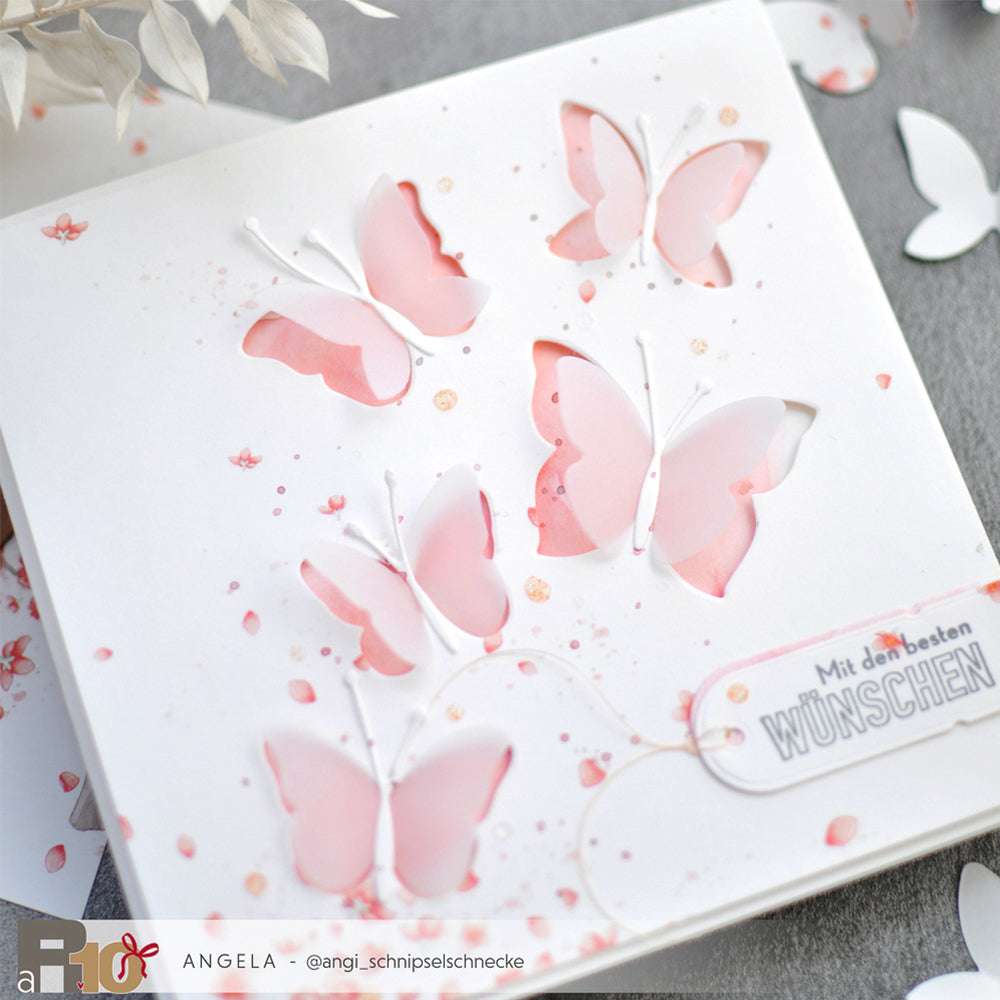 Handgefertigte Karte von Alexandra Renke mit rosa und weißen Schmetterlingsausschnitten aus einer Motivstanze Schichtschmetterling, mit einem "Wünschen"-Gruß unten rechts.