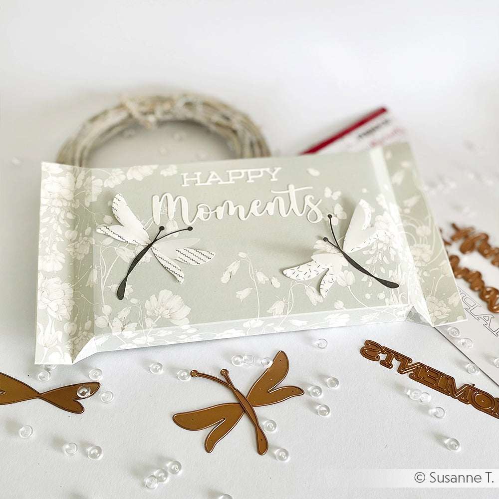 Geschenkbox von Alexandra Renke mit dem Text "Happy Moments", Libellenmotiven aus der Motivstanze Schichtlibelle sowie Zierperlen und Stanzungen, die elegant um die Box herum angeordnet sind.