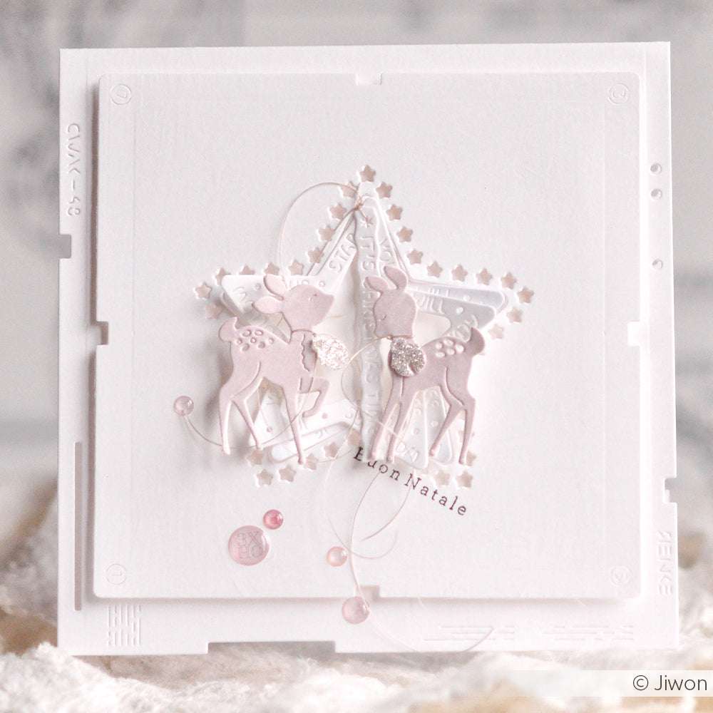 Weihnachtskarte von Alexandra Renke in zartrosa und weiß, mit zwei Rehen, einem mit DieCut Systemen ausgeschnittenen Stern und dem Text "Buon Natale" auf der Vorderseite.