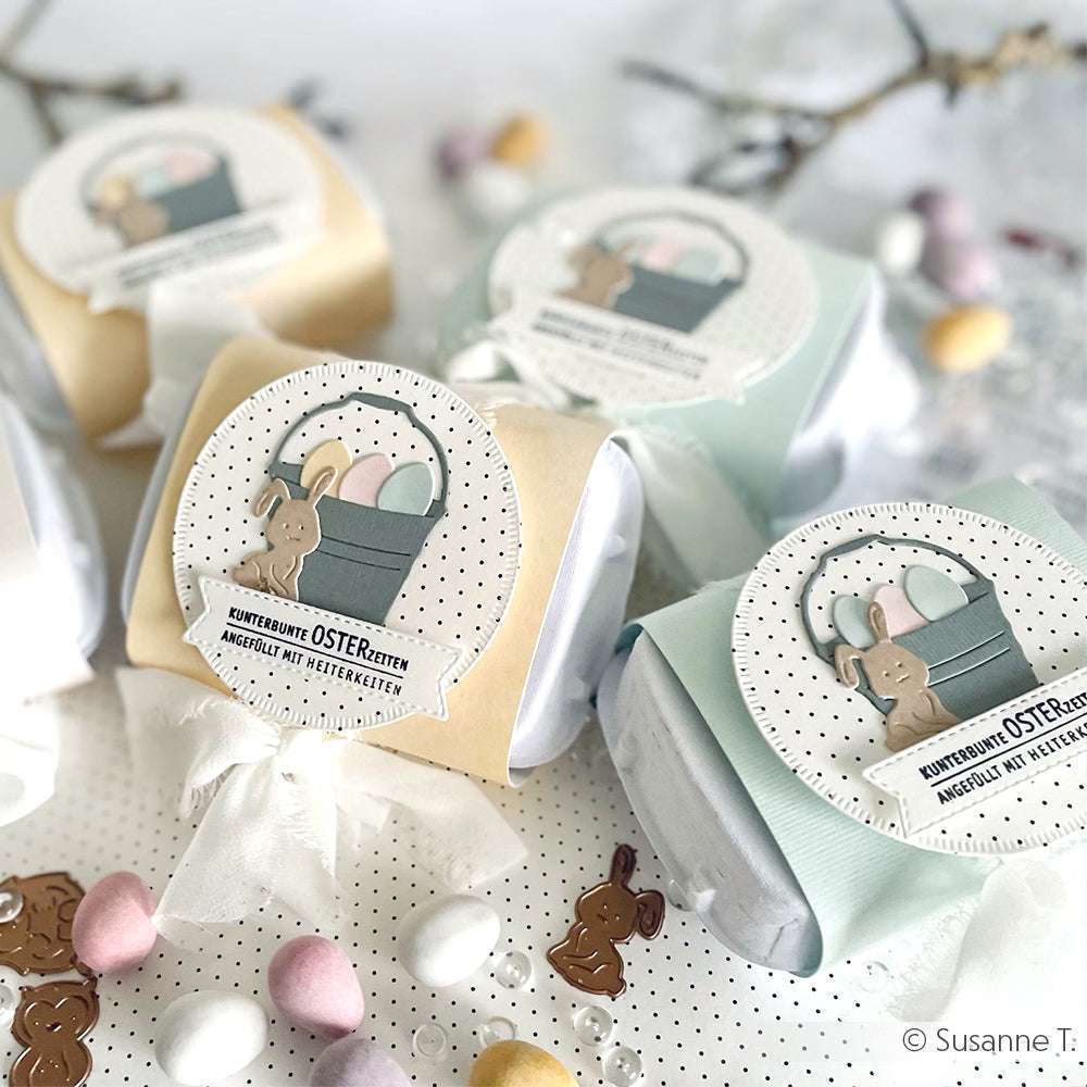 Ostergeschenkboxen in Pastellfarben, verziert mit Hasen und Eiern mit Alexandra Renke Motivstanze Mini Tier Set Dies, umgeben von kleinen Schokoladeneiern.