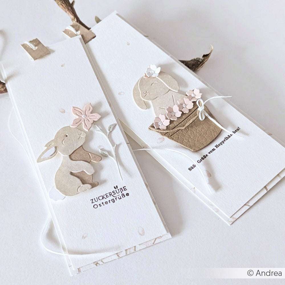 Zwei handgefertigte Osterkarten von Alexandra Renke zeigen niedliche Hasenmotive, die mit Designpapieren und der Motivstanze Schichttier Hase gestaltet wurden, akzentuiert durch pastellfarbene Blumendekorationen auf weißem Hintergrund.