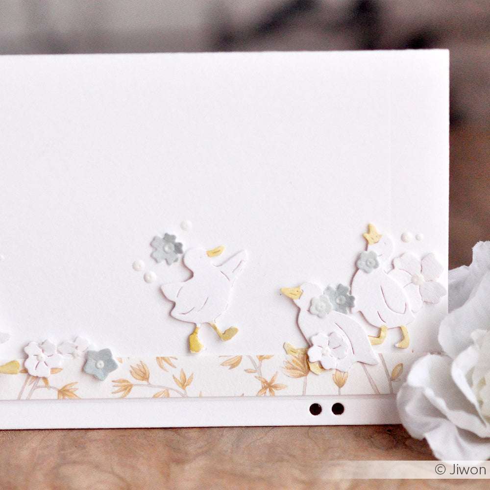 Weiße Karte von Alexandra Renke mit geprägten Enten, kleinen Blumen und goldenen Blättern am unteren Rand - ideal, um Ihre Lieblingsdesignpapiere hervorzuheben oder mit einem Motivstanze Mini Küken Set zu verwenden.